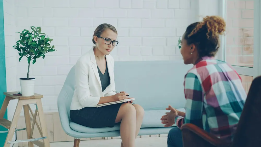 Psicóloga conversando com uma paciente em uma sala clara